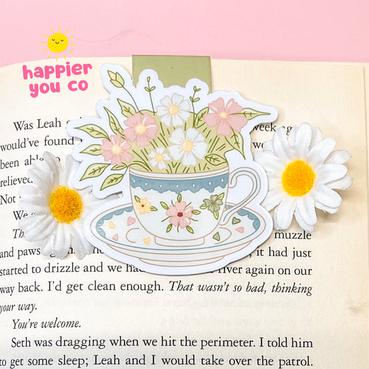 Decorative magnetic bookmark of a teacup with flowers on a book page.