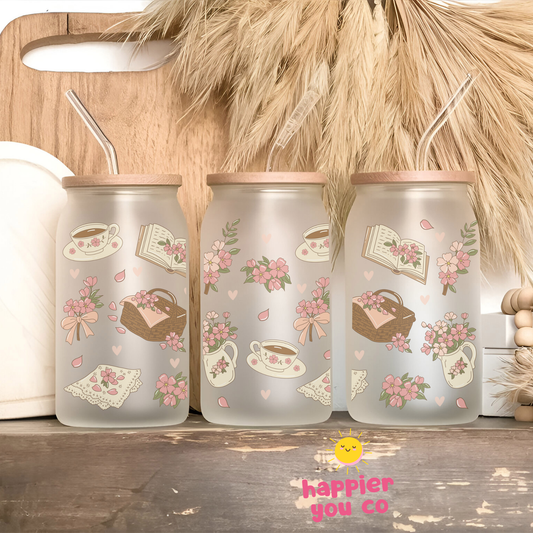 Three frosted glass tumblers with decorative designs on a wooden surface, featuring the brand 'happier you co'.