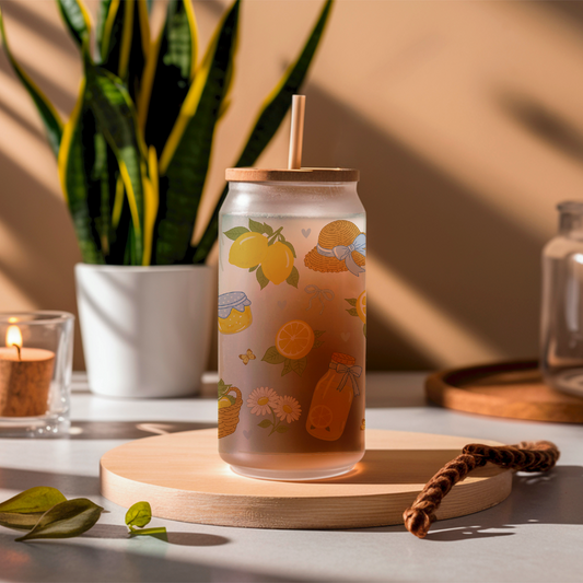 Clear glass tumbler with lemon design on a wooden coaster, surrounded by decorative items.