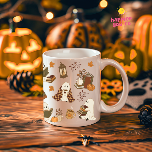 A white ceramic mug with a cute Halloween-themed illustration of a dog ghost and pumpkins, set on a wooden table with a warm, festive background of jack-o'-lanterns and fairy lights. A 'happier you co' logo is visible in the top right corner.