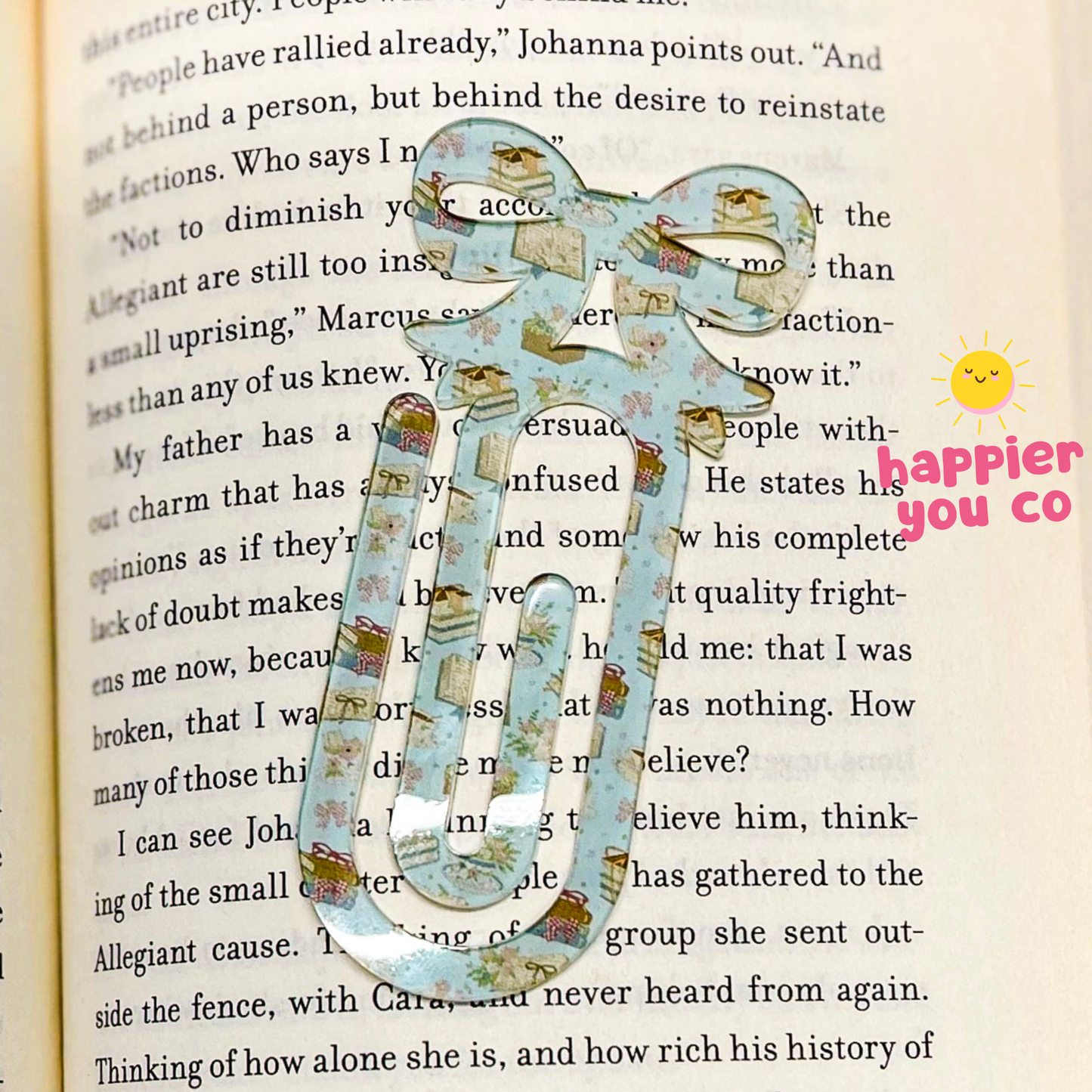 Decorative paper clip on a book with 'happier you co' branding.